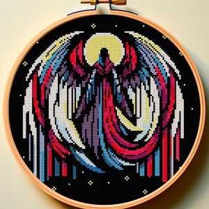Può includere: Un ricamo a punto croce colorato che raffigura una figura stilizzata con ali su uno sfondo nero con stelle bianche.