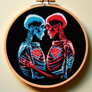 May include: Embroidered cross-stitch hoop art featuring two skeletons in a romantic embrace. The skeletons are rendered in a pixelated style, with one skeleton in blue and the other in red.