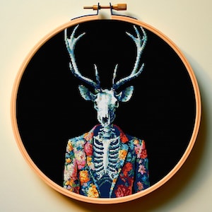 May include: A cross-stitch embroidery of a deer skull wearing a colorful floral patterned suit against a black background.