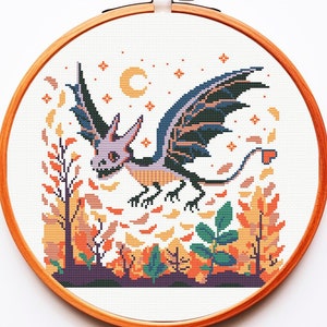 Könnte beinhalten: Kreuzstichmuster mit einem lila und schwarzen Drachen mit orangefarbenen und gelben Blättern im Hintergrund. Der Drache hat einen herzförmigen Schwanz und fliegt in der Luft.