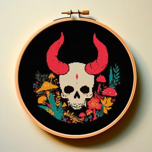 以下が含まれることがあります： 赤い角を持つ骸骨と、カラフルなキノコや葉で囲まれたクロスステッチのデザイン。黒い背景に木製の刺繍枠で飾られたアートワークは、ユニークな壁の装飾を作り出しています。