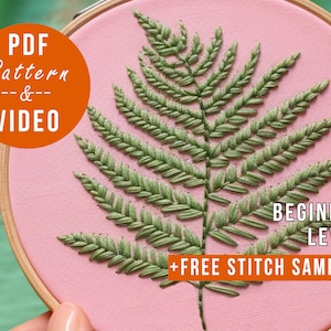 K&ouml;nnte beinhalten: Ein rosa Stickrahmen mit einem gestickten gr&uuml;nen Farnmuster. Der Text "PDF Pattern & VIDEO" befindet sich in einem orangenen Kreis oben links. Der Text "BEGINNER LEVEL + FREE STITCH SAMPLER" befindet sich unten am Rahmen in orange.
