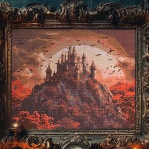 Könnte beinhalten: Ein gerahmtes Kreuzstich-Kunstwerk, das eine dunkle, gotische Burg auf einem Hügel mit einem Vollmond und Fledermäusen zeigt, die am Himmel fliegen. Die Burg ist von Bäumen umgeben und der Himmel ist dunkelrot und orange.