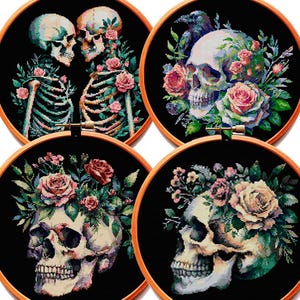 May include: Four circular wooden embroidery hoops containing cross-stitch designs on black fabric. The designs feature human skulls, skeletons, and colorful floral arrangements including pink and white roses, green leaves, and a dark bird.