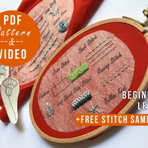 K&ouml;nnte beinhalten: Nahaufnahme eines roten Stickrahmens mit verschiedenen Stichen und dem Text "Back Stitch", "Satin Stitch", "Long Short Satin Stitch", "Running Stitch" und "Button Knot". Der Text "BEGINNER LEVEL" und "+FREE STITCH SAMPLER" ist ebenfalls sichtbar.