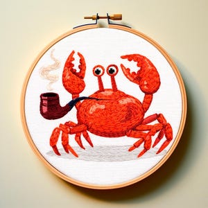 以下が含まれることがあります： 木製のフレームに入った刺繍のカニのアート。カニは鮮やかな赤色で、パイプをくわえています。作品は白い背景にあり、気まぐれな航海をテーマにした作品です。