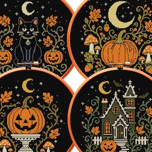 May include: Four circular wooden embroidery hoops containing cross-stitch patterns on black fabric. Designs include a black cat with pumpkins, a large pumpkin with mushrooms, a jack-o'-lantern on a pedestal, and a house, all featuring crescent moons.