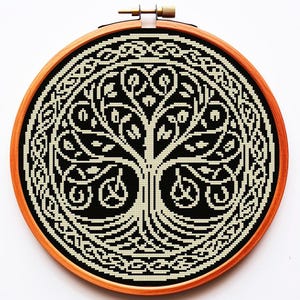 May include: A black and white cross-stitch embroidery of a Celtic tree of life design in a wooden embroidery hoop.