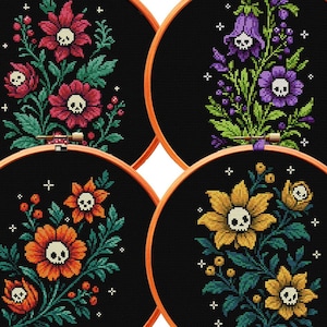 May include: Four circular wooden embroidery hoops containing black fabric with cross-stitched floral designs. Each flower features a small white skull at its center, surrounded by green leaves, berries, and small white cross-shaped star accents.