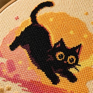 May include: A cross-stitch embroidery project in a round wooden hoop featuring a black cat with large yellow eyes jumping against a circular background of yellow and pink pixels. The design is stitched onto light beige fabric with visible grid holes.