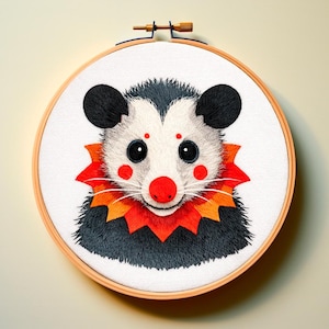 以下が含まれることがあります： 木製のフレームに入った、刺繍されたオポッサムのアートワーク。オポッサムは黒い耳、白い顔、赤い鼻と頬をしています。赤とオレンジの襟を着用しています。刺繍は木製のフレームにセットされています。