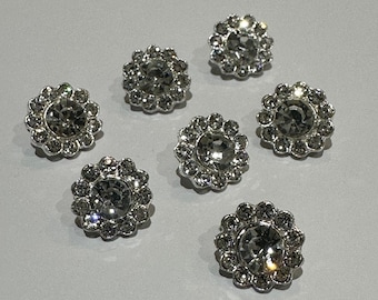 May include: Seven silver-toned, round, rhinestone-encrusted buttons with a flower-like design.