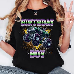 May include: Black t-shirt with a green monster truck graphic and the text "Birthday Boy" in purple and green letters.