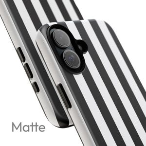 May include: Matte phone case with a black and white striped pattern. The case has a matte finish and features a camera cutout. The word "Matte" is printed on the bottom left corner.