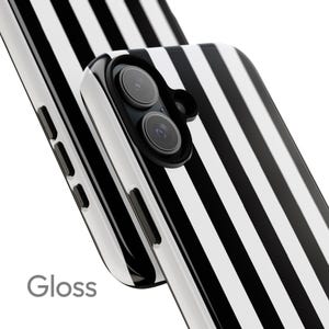 May include: Glossy phone case with a black and white striped pattern. The case has a dual-lens camera cutout and the word "Gloss" is printed on the lower left corner. The case is designed to protect the phone from scratches and damage.