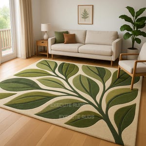 May include: A rectangular area rug with a cream background and a large green leaf design. The leaves vary in shades of green, creating a textured, three-dimensional effect. The rug is placed on a hardwood floor in a living room setting.