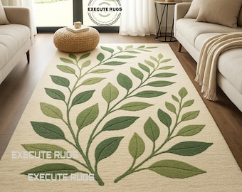 May include: A rectangular area rug with a cream-colored background and a green leaf design. The leaves vary in shades of green and are arranged in a symmetrical pattern. The rug is placed in a living room setting with furniture.