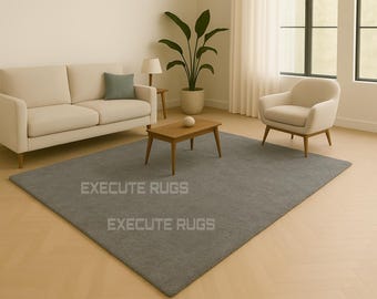 May include: A modern living room setup featuring a gray rectangular rug, a beige sofa with a green pillow, and a matching armchair. A wooden coffee table and a potted plant complete the scene.