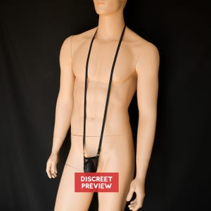 May include: A black lingerie pouch with a black strap hanging around a person's neck. The pouch is made of a mesh material and has a diamond pattern.