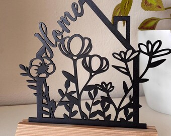 Home stand with flowers and house in black. Approx. 18 cm high and 20 cm wide. Includes wooden blocks to put it in.