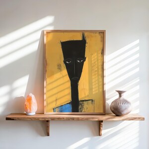 May include: A framed rectangular wall art print featuring a stylised, elongated black figure with a flat-top head against a vibrant yellow background. The figure has a long neck and a blue lower section. The artwork is displayed in a light wood frame.