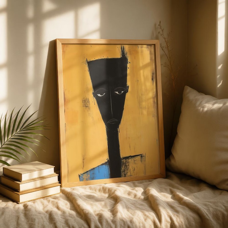May include: A framed wall art print featuring a stylised, elongated black figure with a flat-topped head and neutral expression set against a textured mustard yellow background with a small blue accent at the bottom edge of the figure's torso.