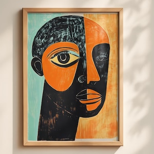 May include: A framed print featuring a stylized portrait of a face divided into two distinct color sections. One side is set against a light blue background with black and orange tones, while the other side features an orange background with black.