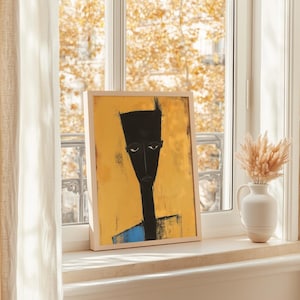 May include: A framed rectangular wall art print featuring a stylised portrait of a figure with a tall, dark, angular head and neck set against a vibrant mustard yellow background, with a small blue section visible at the bottom of the figure.