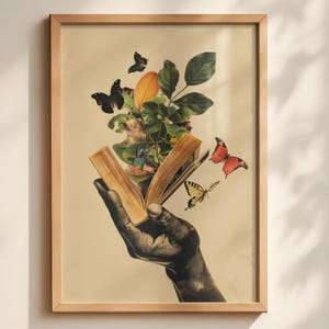 May include: A framed art print featuring a dark-toned hand holding an open book. From the pages of the book, green leaves, a large orange leaf, and several butterflies in black, red, and yellow emerge against a light cream-colored background.