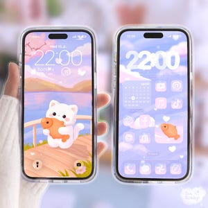 Könnte beinhalten: Zwei transparente Handyhüllen mit pastellfarbenen Hintergrundbildern. Eines zeigt eine weiße Katze mit einem Fisch, das andere einen Kalender und App-Symbole. Die Uhrzeit 22:00 ist auf beiden Bildschirmen zu sehen. Die Hüllen werden in einer Hand gehalten.