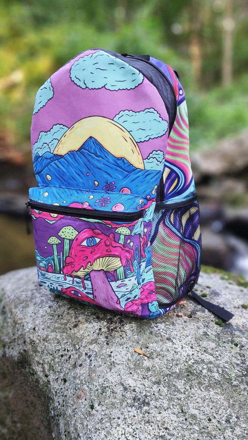 May include: A colorful backpack with a psychedelic design featuring a mushroom, mountains, and a sun. The backpack has a mesh pocket on the side and a zippered pocket on the front.