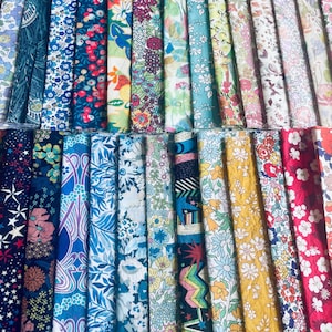 Puede incluir: Una colección de tiras de tela dispuestas en filas, con una diversa gama de patrones coloridos que incluyen motivos florales, botánicos, geométricos y de estrellas en tonos de azul, rojo, amarillo, verde, rosa y blanco sobre textiles.