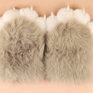 May include: A pair of grey and white furry paw-shaped slippers with claws.