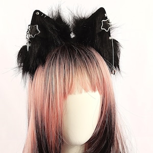 May include: Black faux fur cat ears headband with star-shaped metal accents and dangling charms.