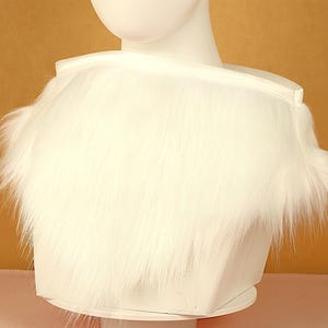 Pode incluir: Colete de pele sintética branca com forro de cetim. O colete é macio e felpudo, e seria uma ótima adição a qualquer roupa de inverno.