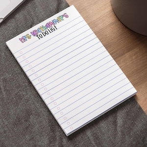 May include: A white rectangular notepad with horizontal blue lines and a column of pink circular checkboxes on the left side. The top of the page features the text Mrs Neathammer's TO DO LIST in colorful, bubble-style lettering with a black outline.