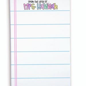 May include: White notepad with blue horizontal lines and pink vertical lines on the left side. The text "from the desk of... MRS HANNAH" is printed at the top in colorful bubble letters. The notepad is rectangular.