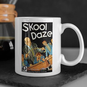 Könnte beinhalten: Weiße Keramiktasse mit einer Schwarzweißillustration eines Lehrers mit einem Lineal und Schülern in einem Klassenzimmer. Der Text "Skool Daze" ist in Weiß auf schwarzem Hintergrund gedruckt. Die Tasse hat einen schwarzen Griff.