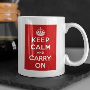May include: White ceramic mug with a red background and the text "Keep Calm and Carry On" in white. A crown is above the text.