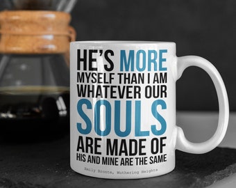 May include: White ceramic mug with a black and blue quote from Emily Bronte's Wuthering Heights: "He's more myself than I am whatever our souls are made of his and mine are the same."