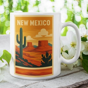May include: White ceramic mug featuring a New Mexico landscape design. The design includes a saguaro cactus, mesas, and the text "NEW MEXICO" in an orange and brown color scheme. The mug has a curved handle.