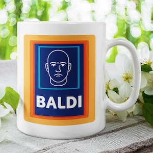 Puede incluir: Taza de cerámica blanca con un diseño que presenta una ilustración de cabeza calva y la palabra "BALDI" en letras mayúsculas blancas. El diseño está dentro de un marco rectangular azul y naranja. La taza está sobre una mesa con flores blancas.