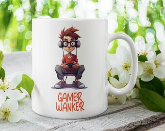 May include: White ceramic mug with a cartoon illustration of a person wearing headphones and holding a video game controller. The text "GAMER WANKER" is printed in orange below the illustration.