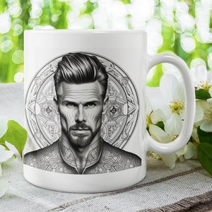 Puede incluir: Taza de cerámica blanca con una ilustración en blanco y negro de la cara de un hombre con barba y un patrón geométrico alrededor.