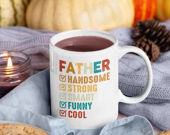 May include: White ceramic mug with a brown liquid inside. The mug has the text "FATHER" in large letters and a checklist with the words "HANDSOME", "STRONG", "SMART", "FUNNY", and "COOL" underneath.