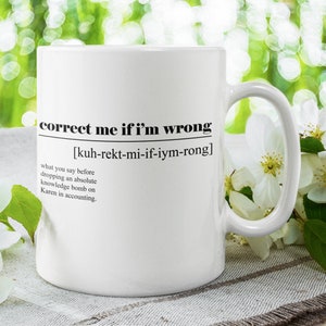 Op de afbeelding: Witte keramische mok met zwarte tekst die luidt: "corrigeer me als ik het mis heb [kuh-rekt-mi-if-iym-rong] wat je zegt voordat je een absolute kennisbom op Karen in de boekhouding laat vallen."
