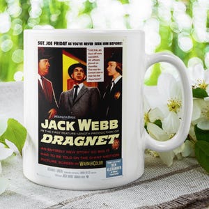 May include: White ceramic mug featuring a movie poster for "Dragnet" starring Jack Webb. The poster has a vintage design with text and images of actors. The mug is set against a blurred green background with white flowers.
