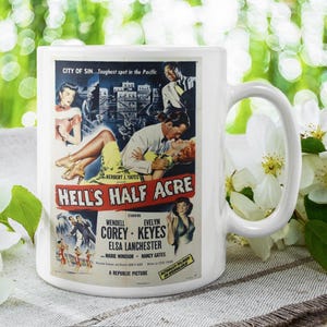 May include: White ceramic mug featuring a vintage movie poster for "Hell's Half Acre." The poster art includes a couple embracing, with text that reads "City of Sin." The mug is set against a blurred green background with white flowers.