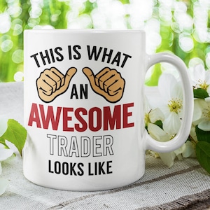May include: White ceramic mug with a black and red design that says "This is what an awesome trader looks like". The mug has two thumbs up symbols on either side of the text.