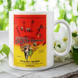 May include: White ceramic coffee mug with a colorful image of the movie "Invasion of the Body Snatchers" featuring the text "Walter Wanger presents the amazing in CinemaScope" and "Kevin McCarthy Dana Wynter".